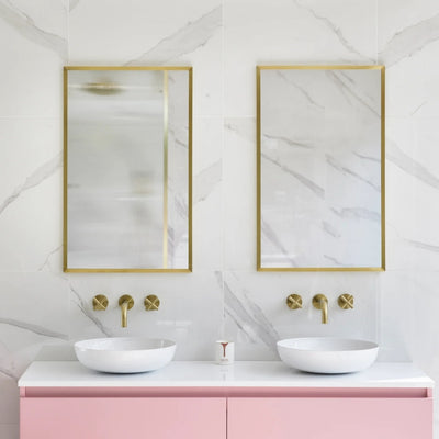 Rectangular mirrors in brushed brass above a bathroom vanity basin